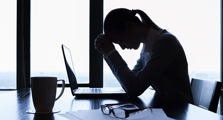 Female employee grieving at work and looking up resources available at the office to support her.