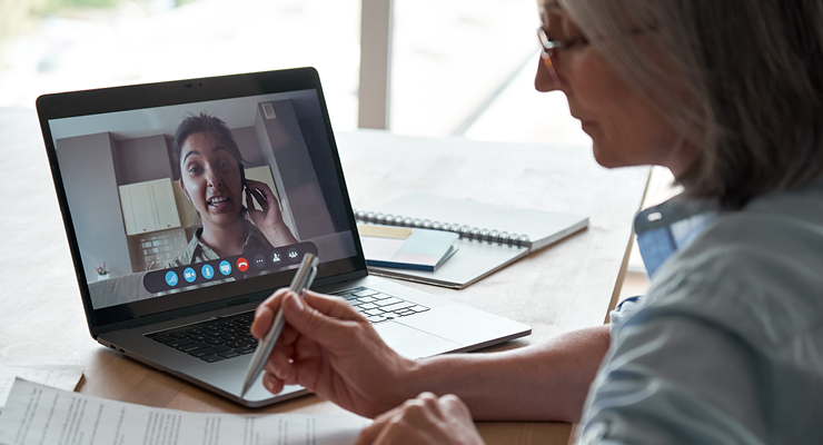 Female paralegal exploring tips for remote depositions with a coworker on her laptop.