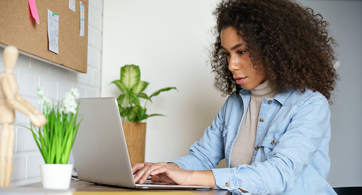 Female African American woman taking a standardized online test on her laptop preparing for college.