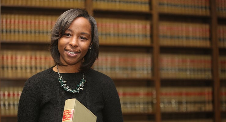 A female paralegal smiling and holding a book.