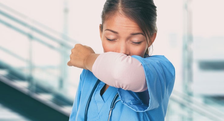 woman health professional coughing into her elbow to prevent spreading germs