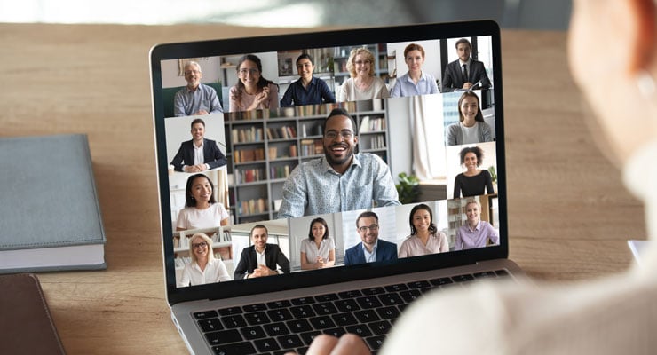 an over-the-shoulder view of a laptop screen with a group of coworkers in a video call