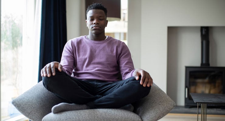 male student practicing meditation techniques to stay mindful on test day