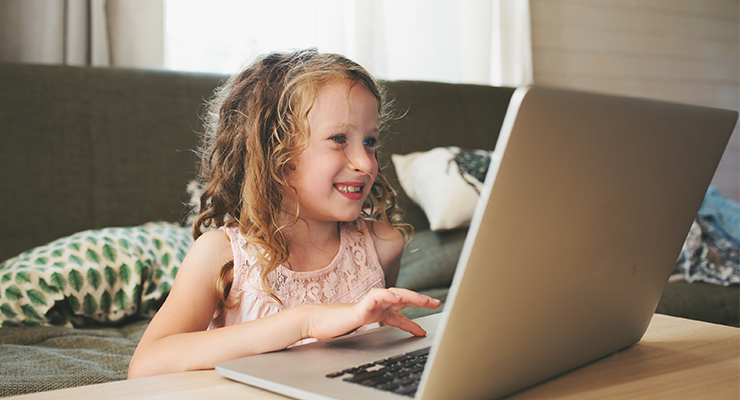 A young girl using a laptop at home.