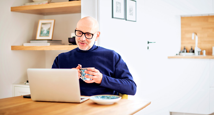 A male drinking a hot drink while working from home.