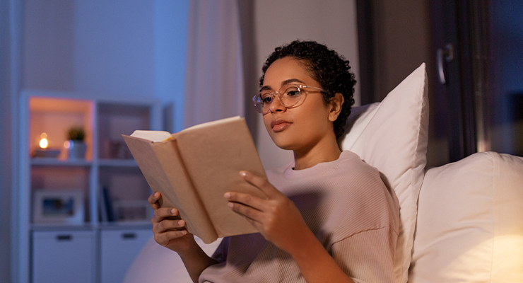 student in bed studying before going to sleep