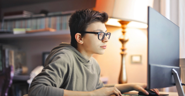 Middle school kid wearing glasses in front of his computer learning about cybersecurity