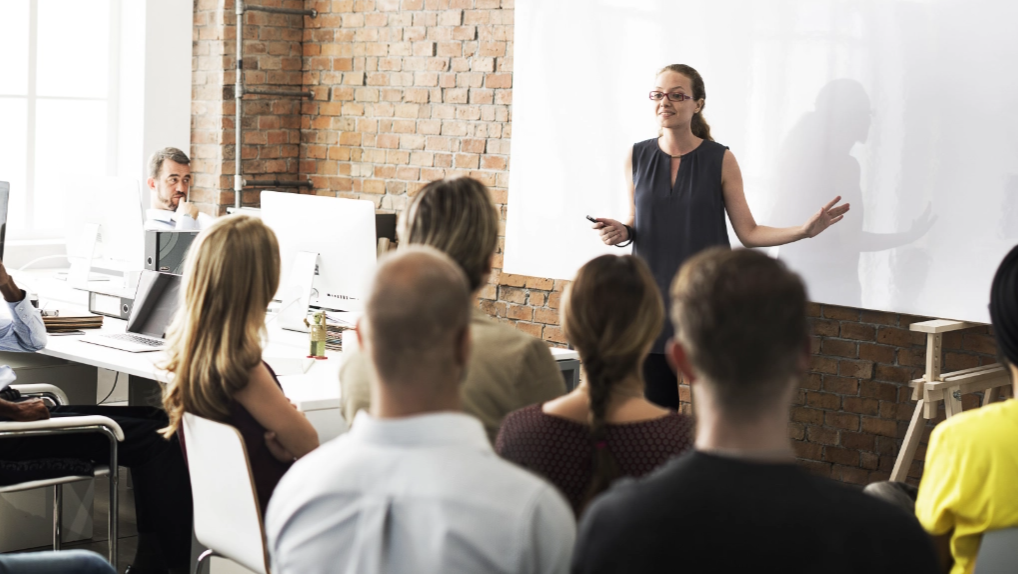 Woman giving a professional education presentation to a group of employees.